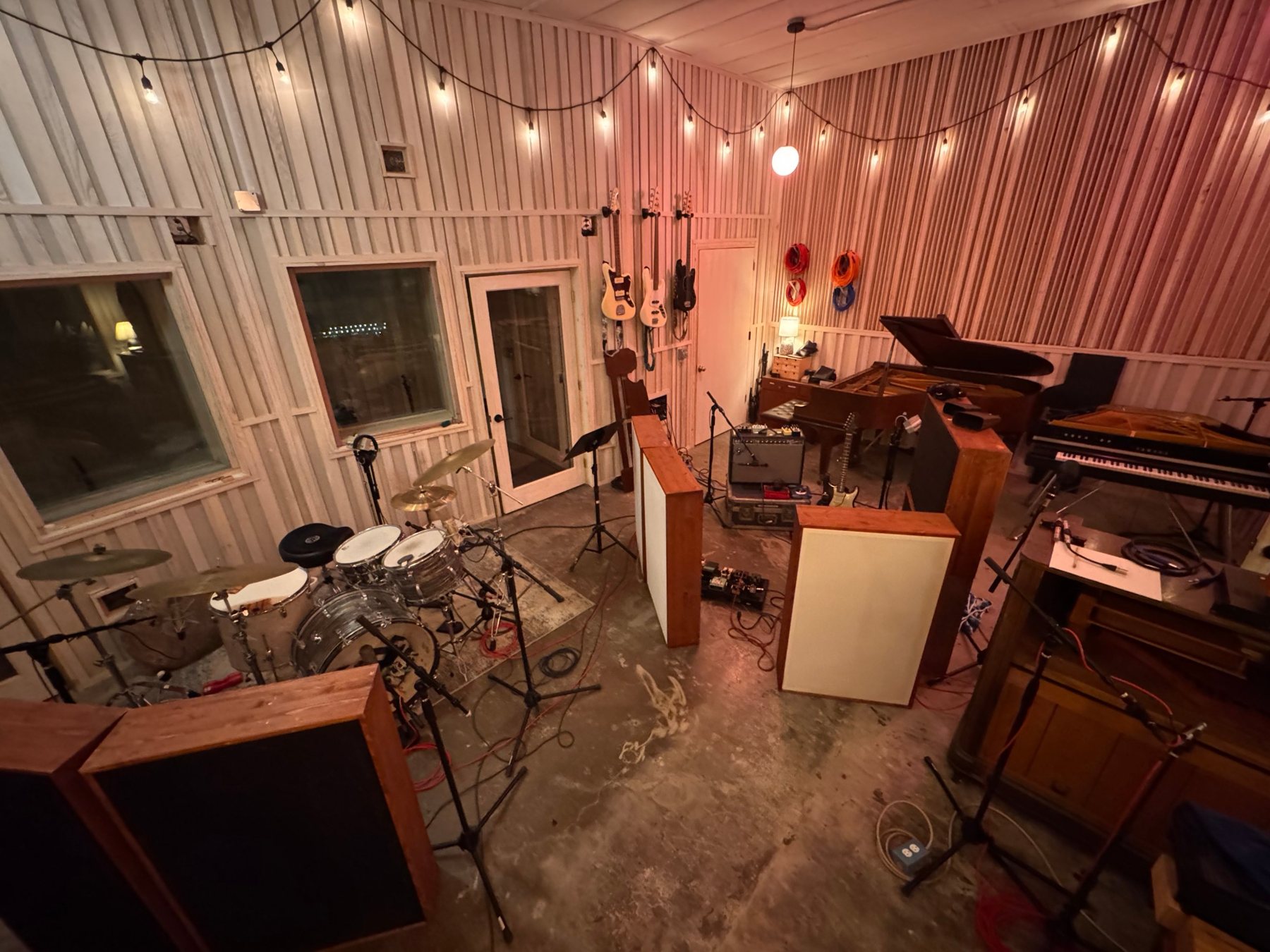 The Hotel Earth live room: drum kit, gobos, grand piano, CP-70 and guitars on the wall